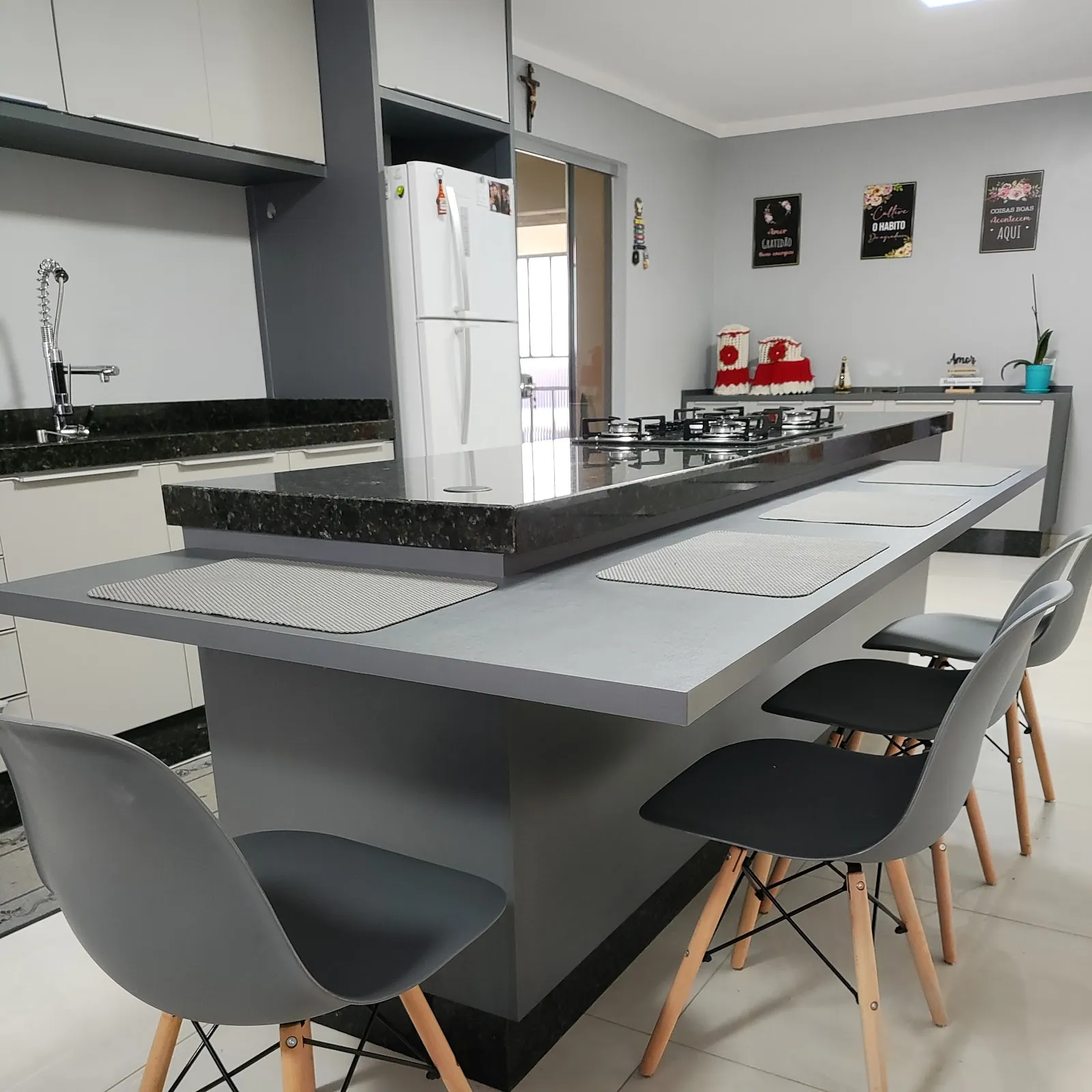 Cozinha com ilha cinza, cooktop e bancada em granito